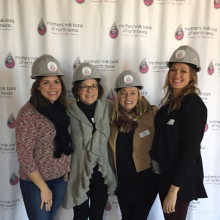 Four women in hard hats in front of logo step and repeat screen