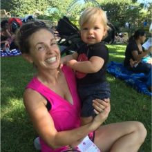 Mother holding toddler son while sitting in park
