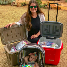 Mother and baby posed next to two coolers of breastmilk