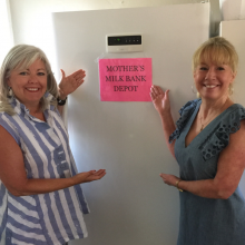 Two women standing on either side of an upright freezer