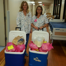 Two nurses standing with coolers full of donated breastmilk from their depot