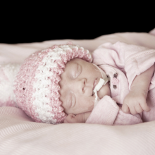 Premature baby wearing pink hat and onesie
