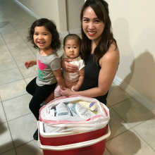 Mother, baby and toddler next to a cooler full of frozen breastmilk