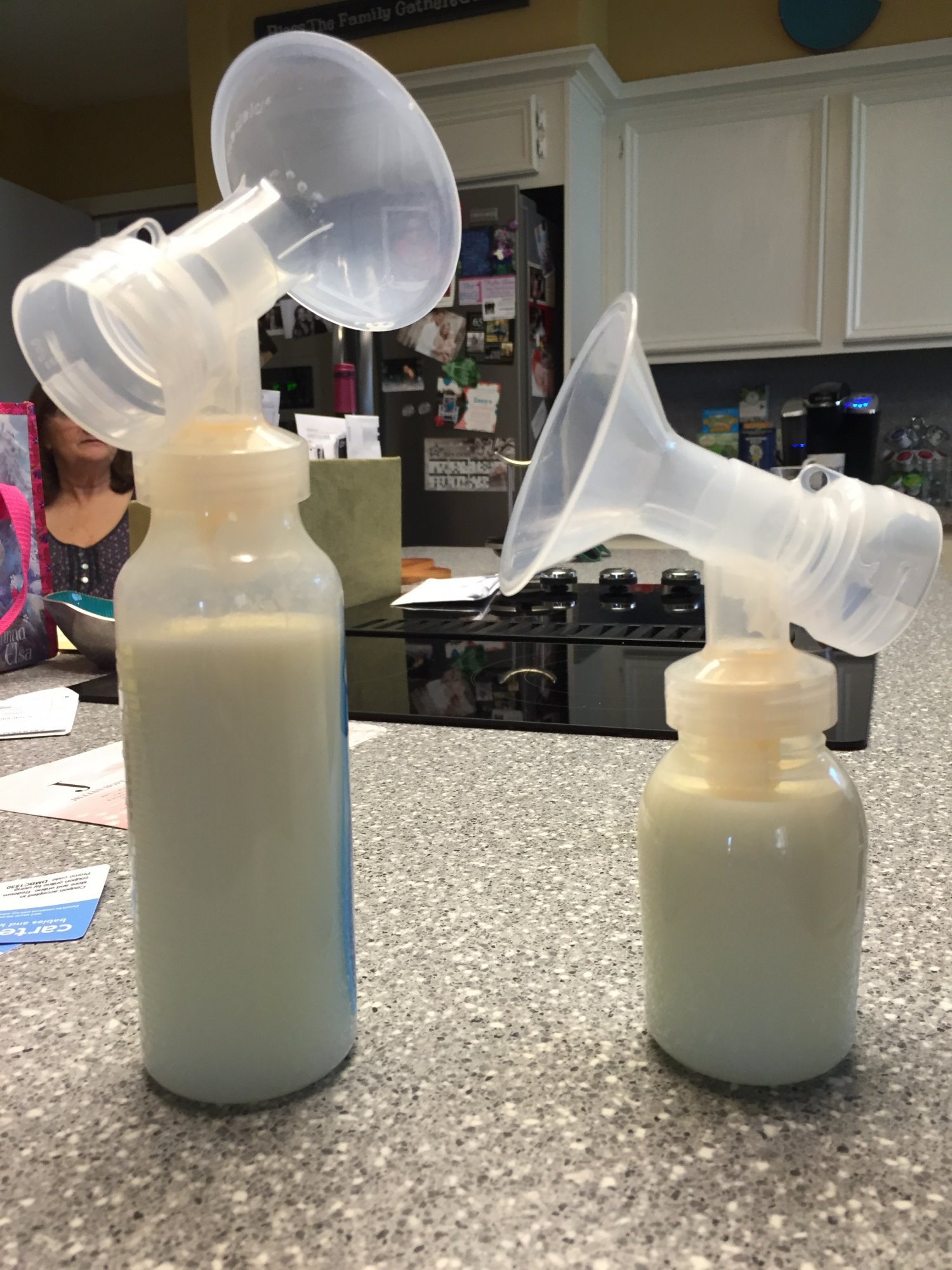 Two bottles of recently pumped breastmilk, still attached to pump parts