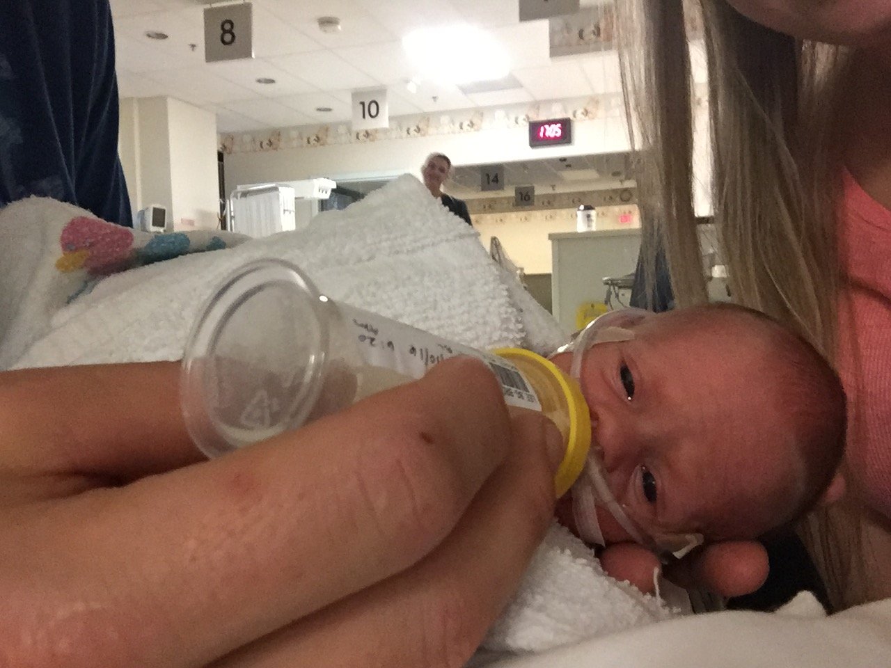 Premature baby with bottle of donor milk