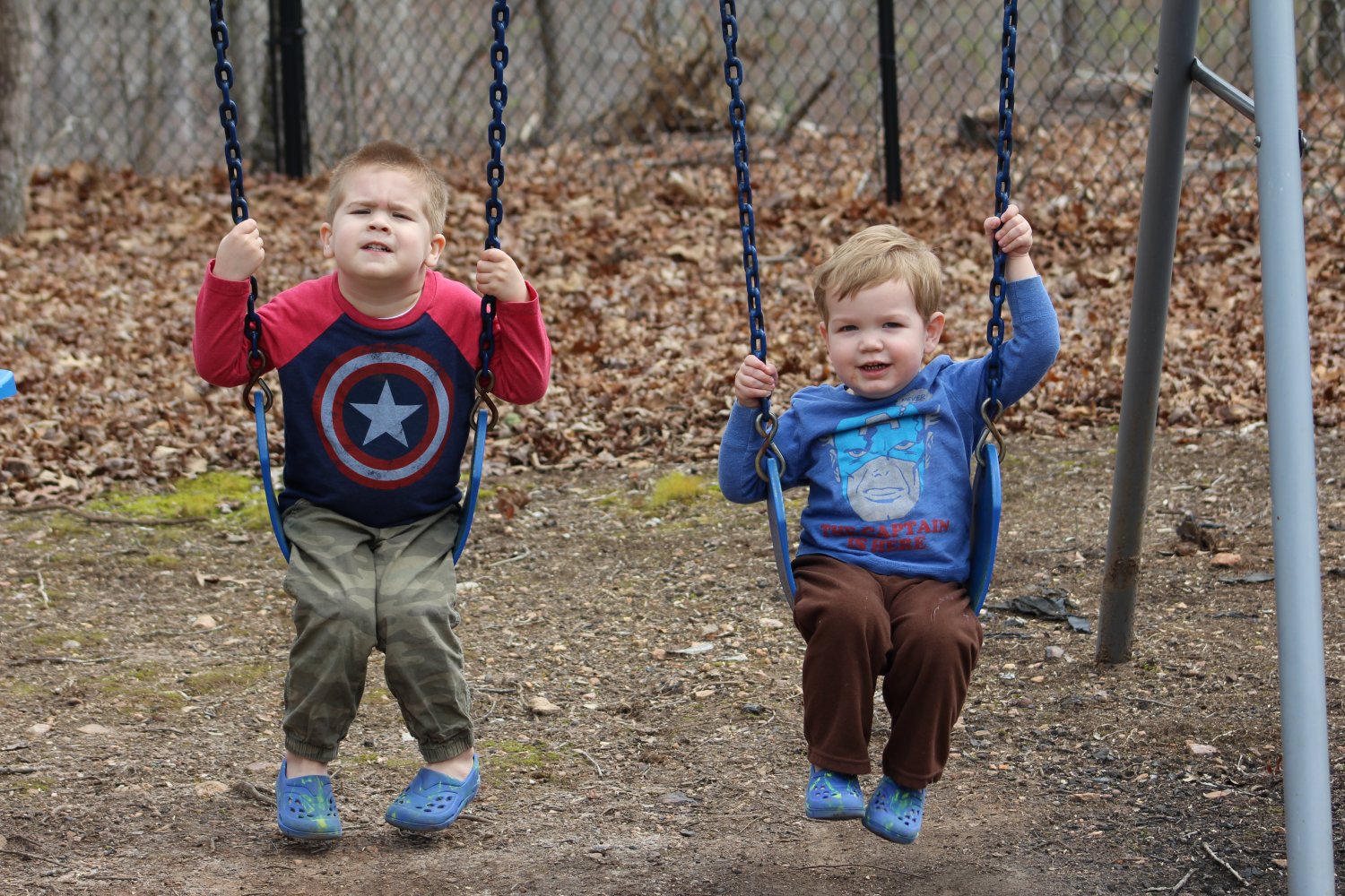 Two toddler brothers on swings