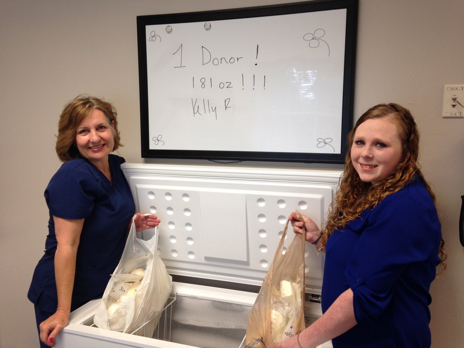 Mother and nurse posing with mother's two grocery sacks of donated breastmilk