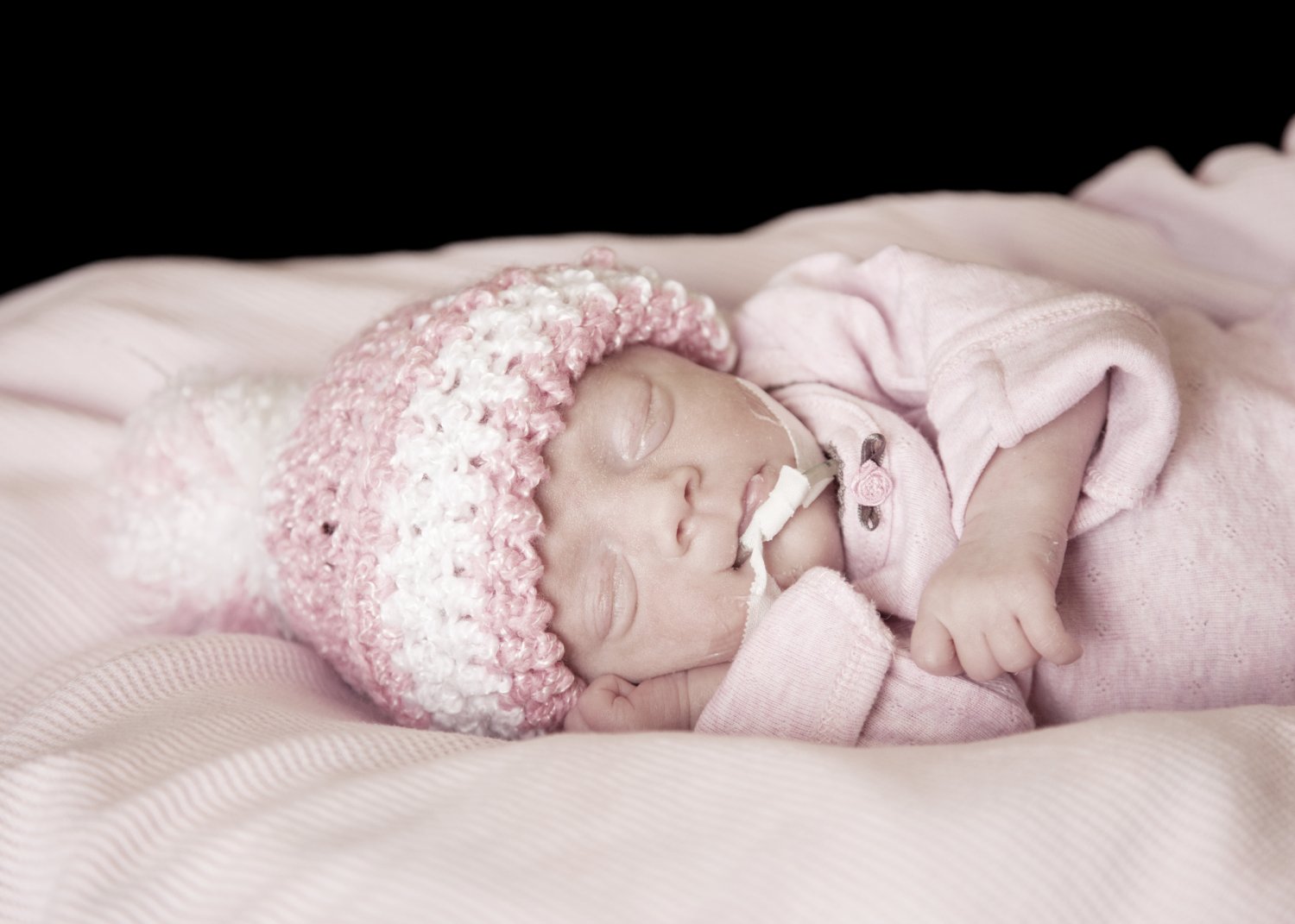 Premature baby wearing pink hat and onesie