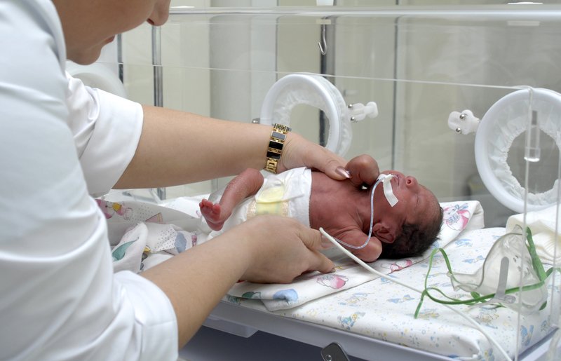 Premature baby being picked up by nurse