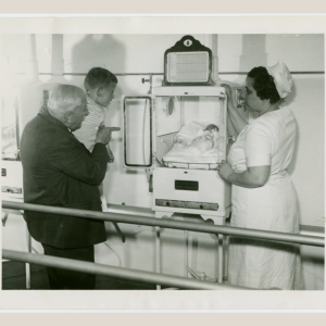 Martin and Hildegarde Couney with boy looking at baby in incubator 