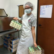 Lab technician holding two cases of recently pasteurized donor milk