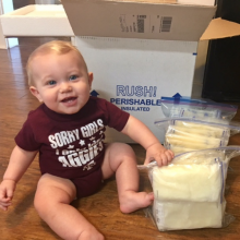 Baby sitting next to bags of frozen breastmilk