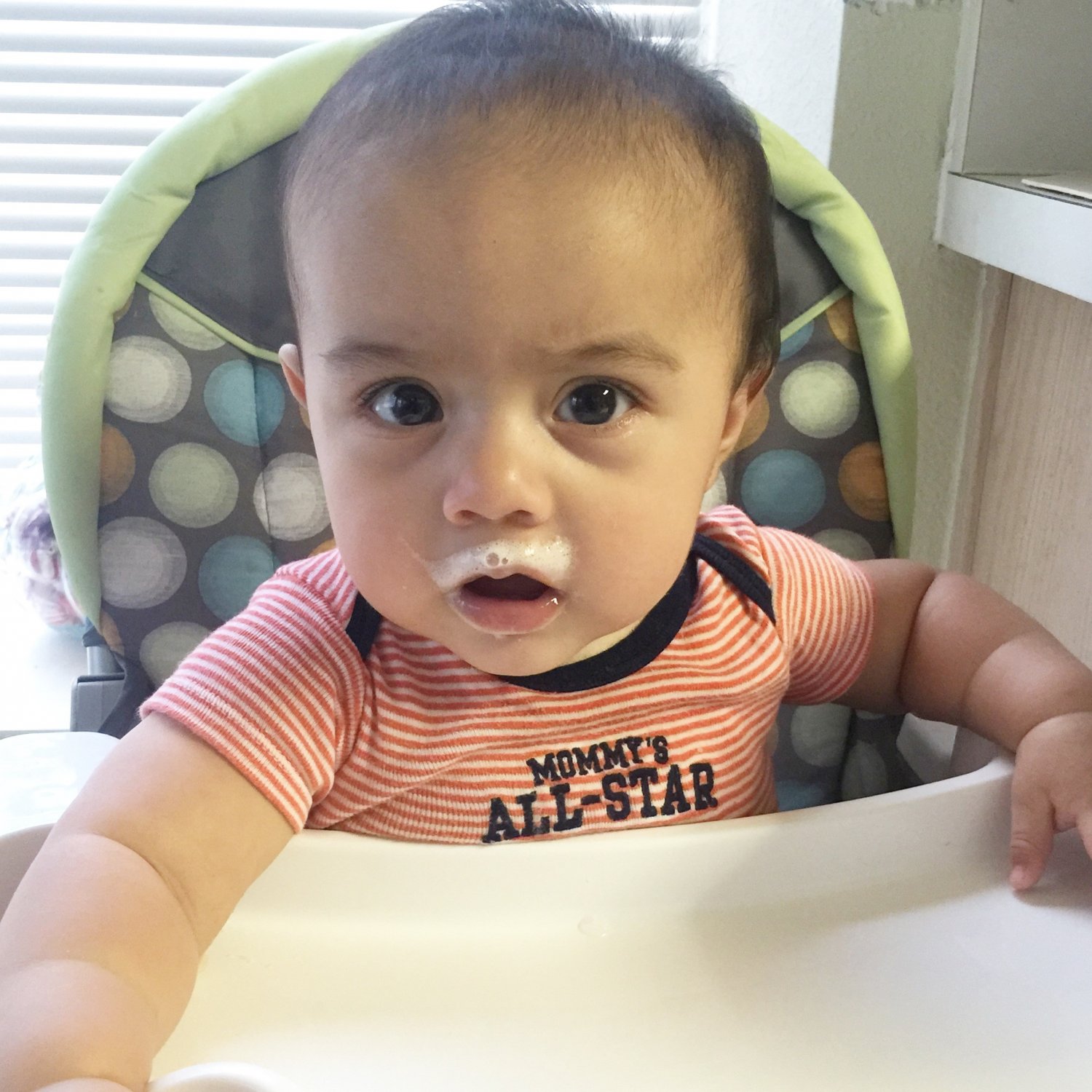 Baby in high chair with milk mustache