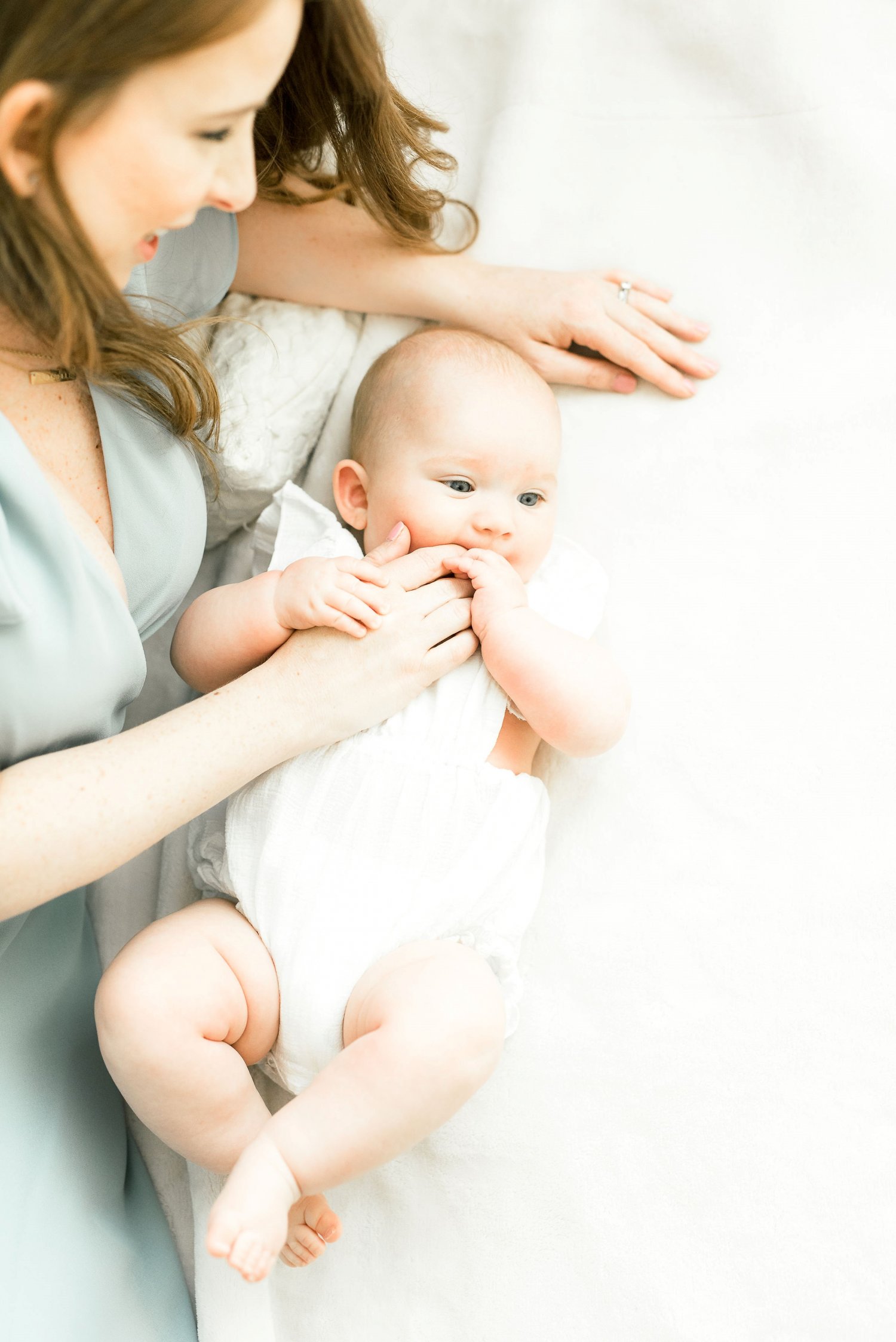 Mother laying next to baby on a white sheet