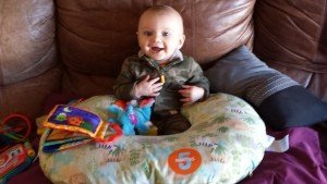 Baby on couch surrounded by toys