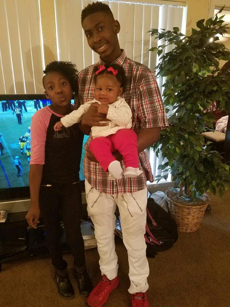 Older brother holding baby sister, middle sister standing next to them