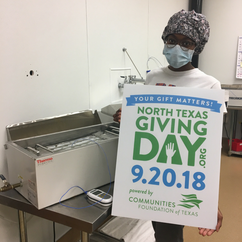 Lab technician holding sign while standing next to pasteurizer