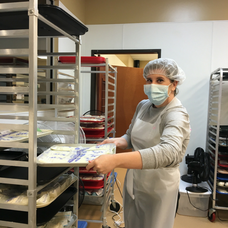 Lab volunteer pulling out a tray of thawed milk bags