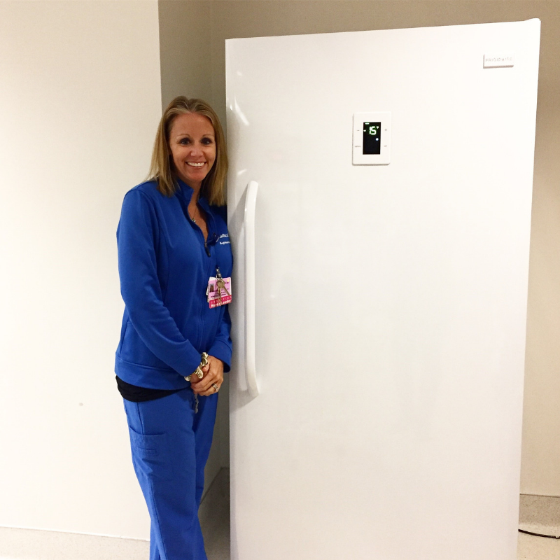 Woman standing next to upright freezer