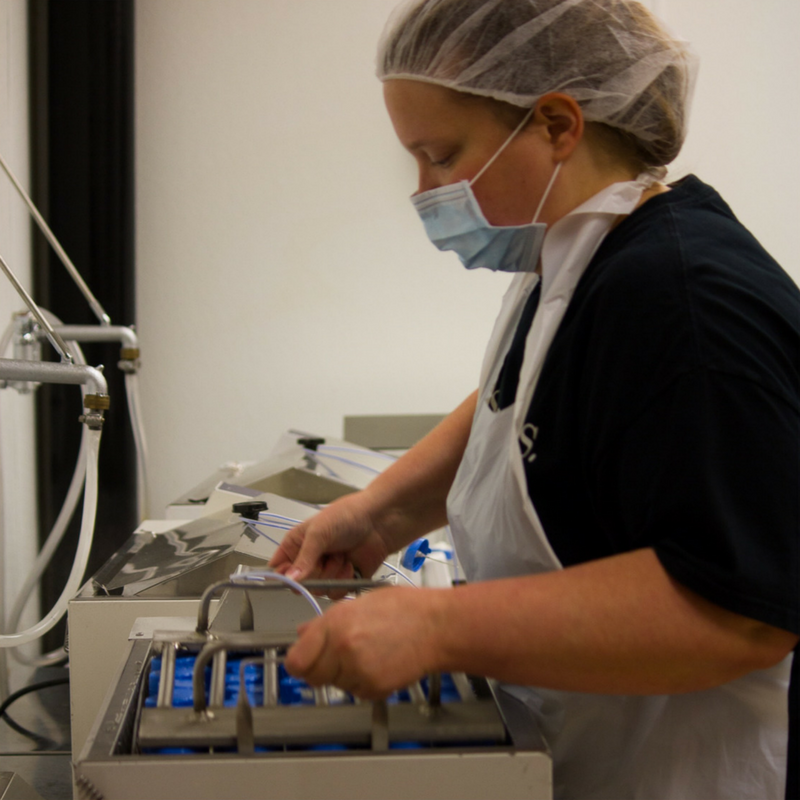 Lab technician removing a tray of bottles from a shaking water bath