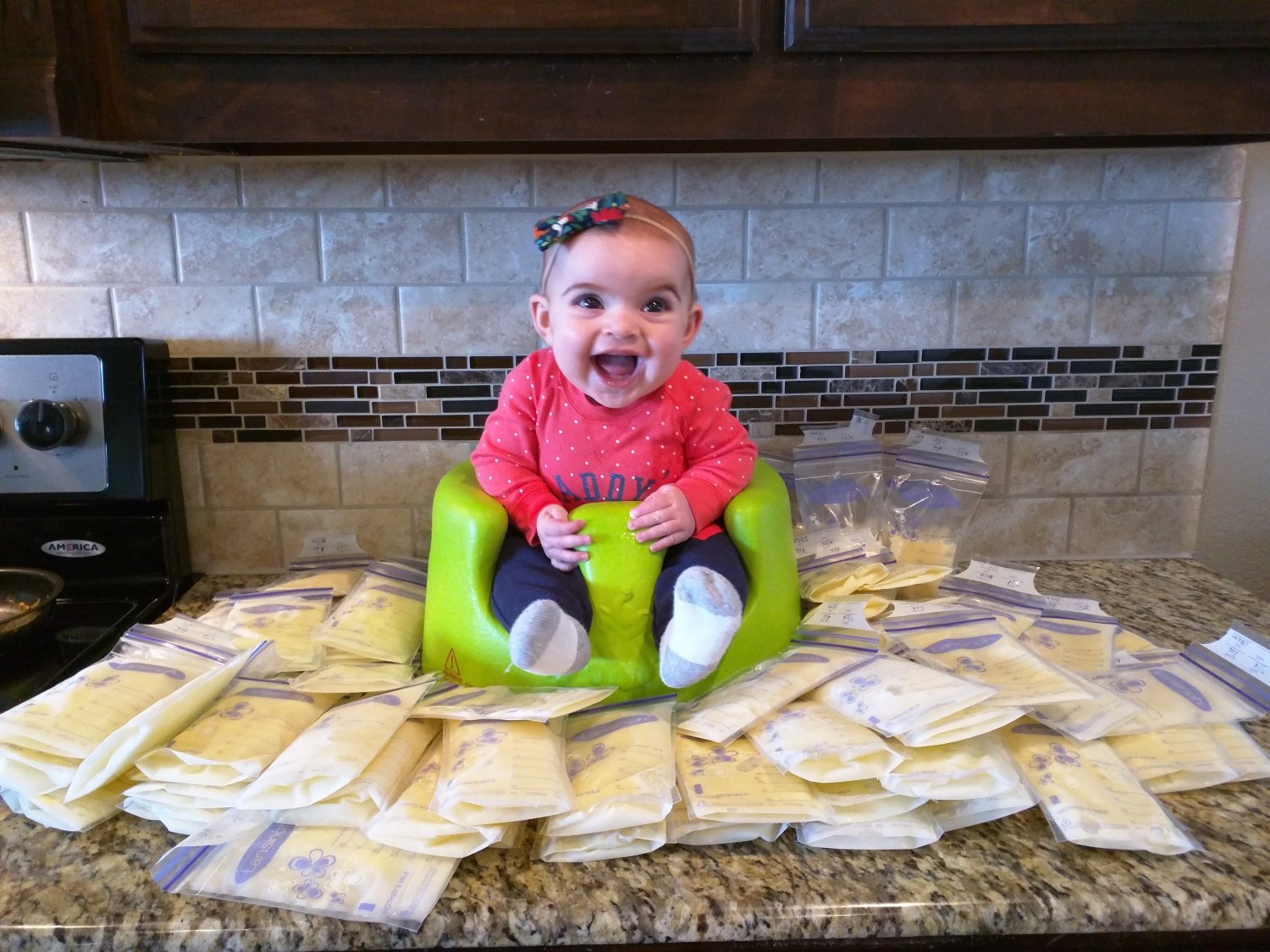 Baby sitting among frozen bags of pumped breastmilk