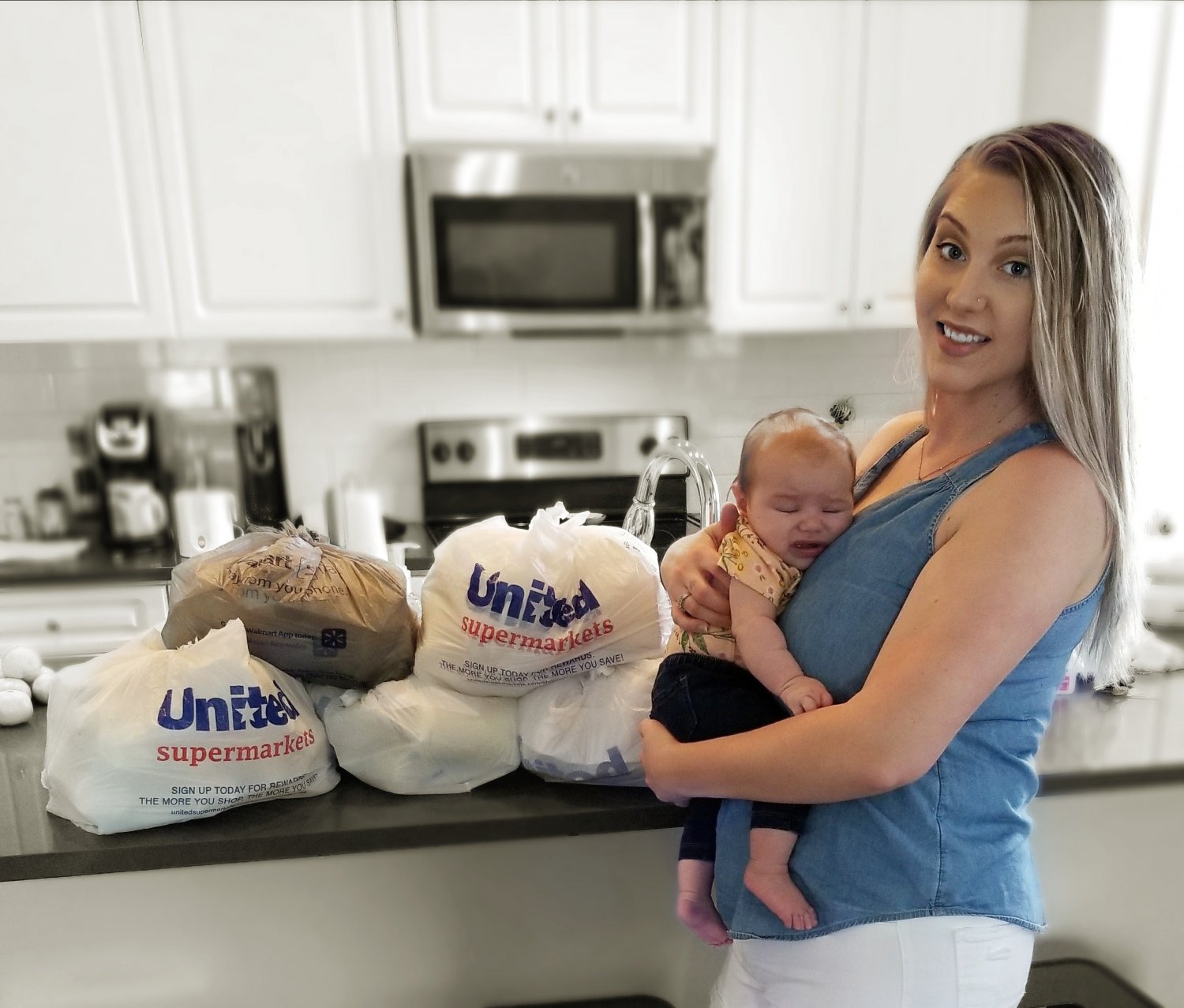 Mother holding baby and standing next to her donated breastmilk