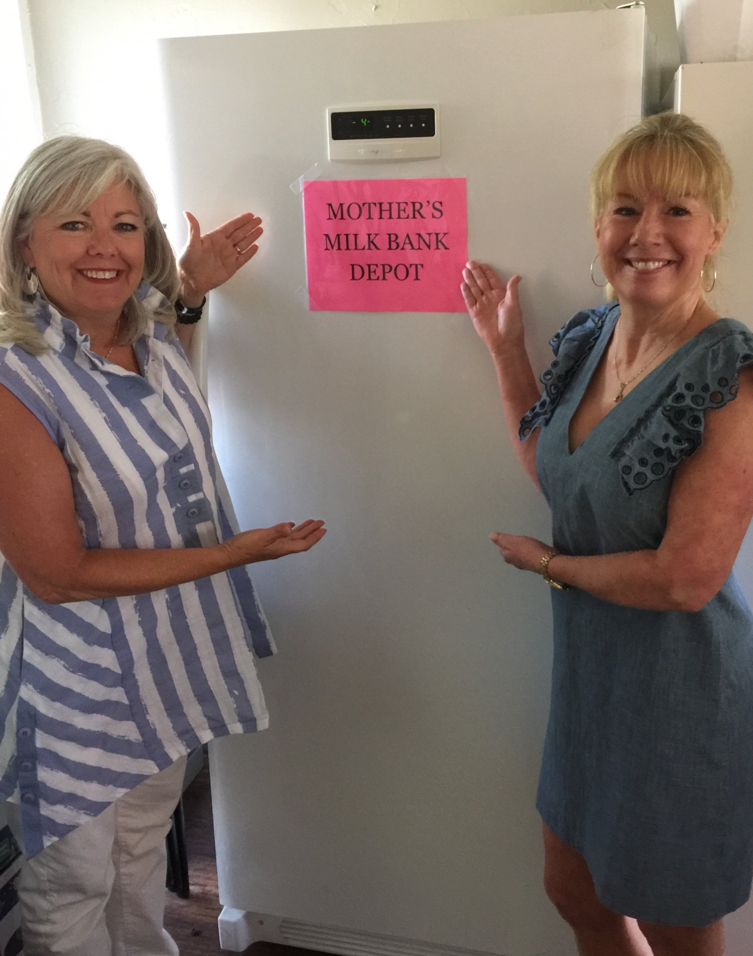 Two women standing on either side of a standing freezer