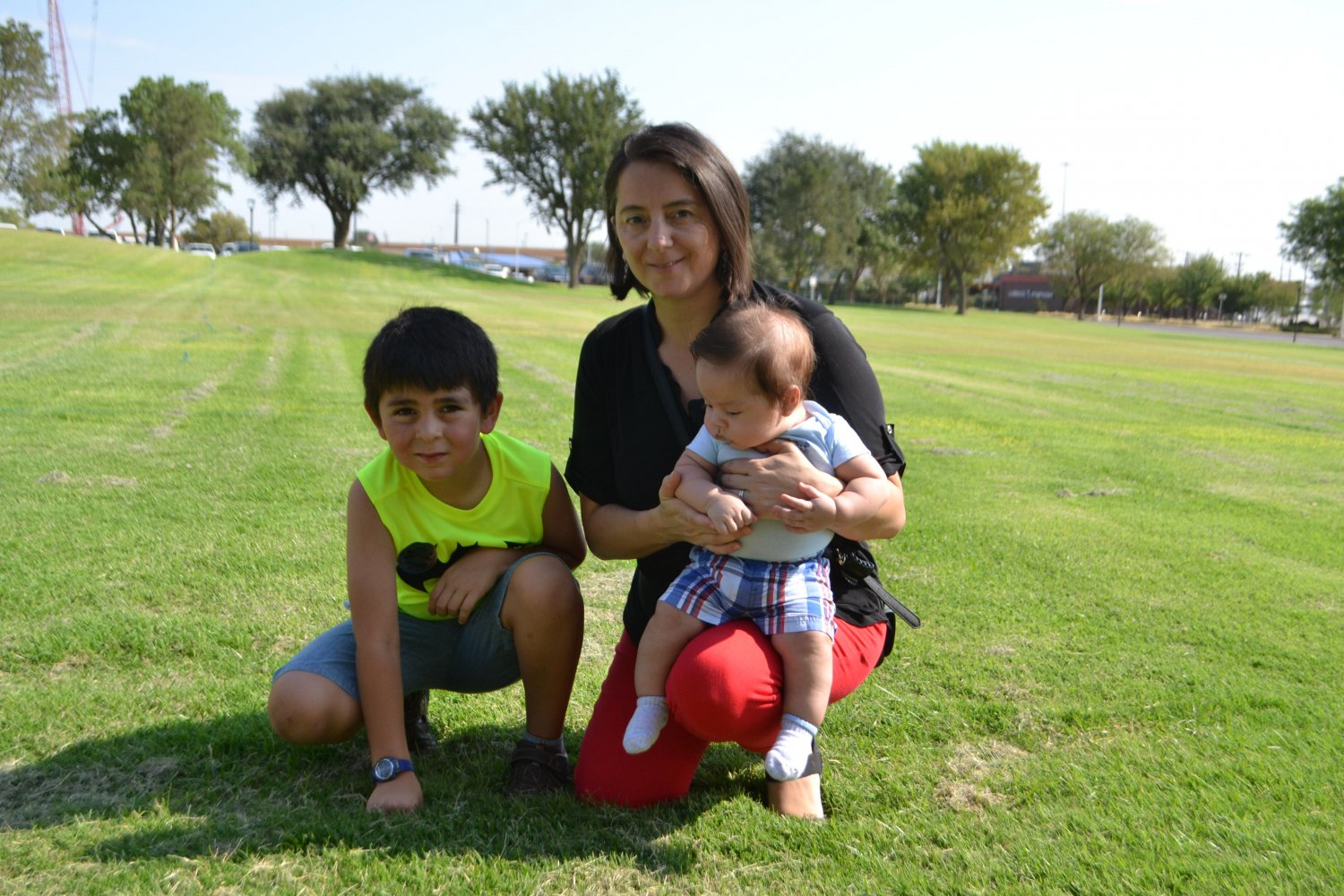 Mother holding infant son, older son sitting next to her