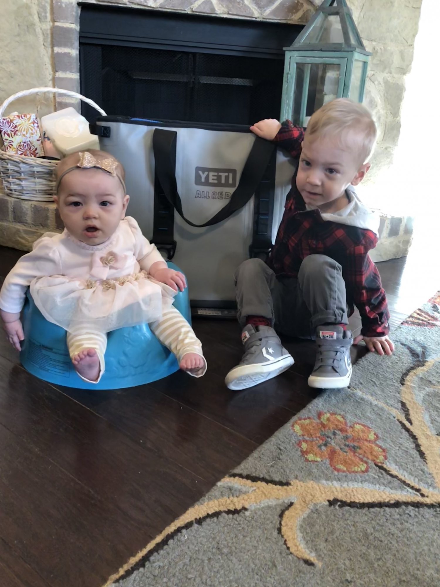 Baby and toddler next to cooler full of frozen breastmilk