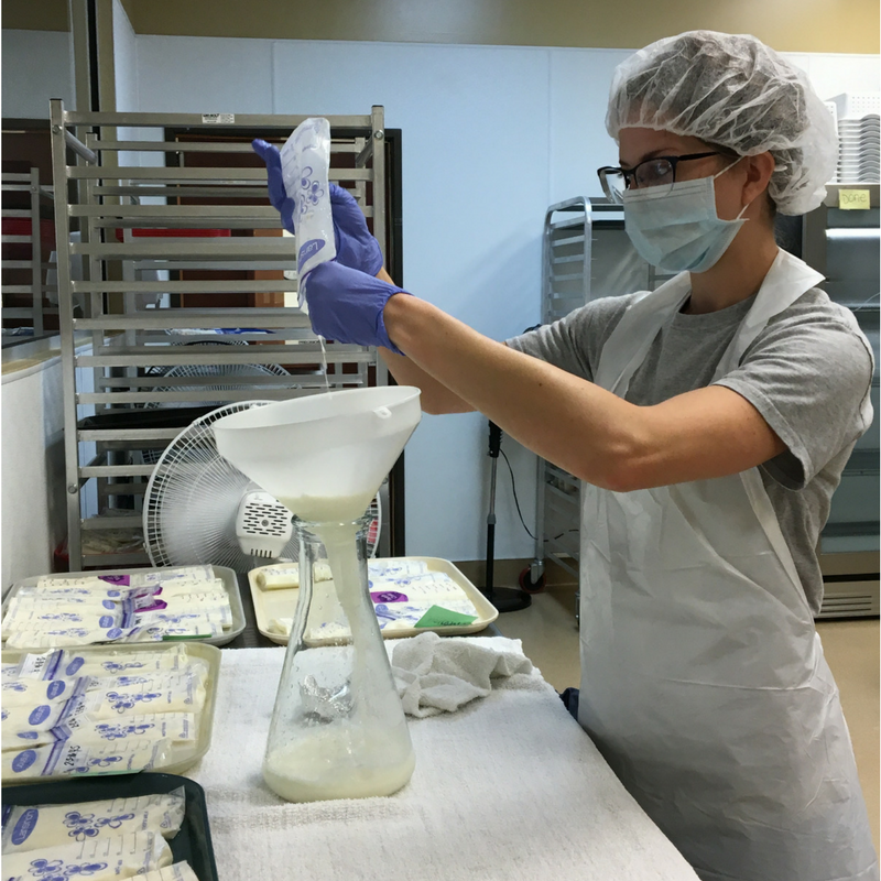 Lab technician pouring donated breastmilk into a flask