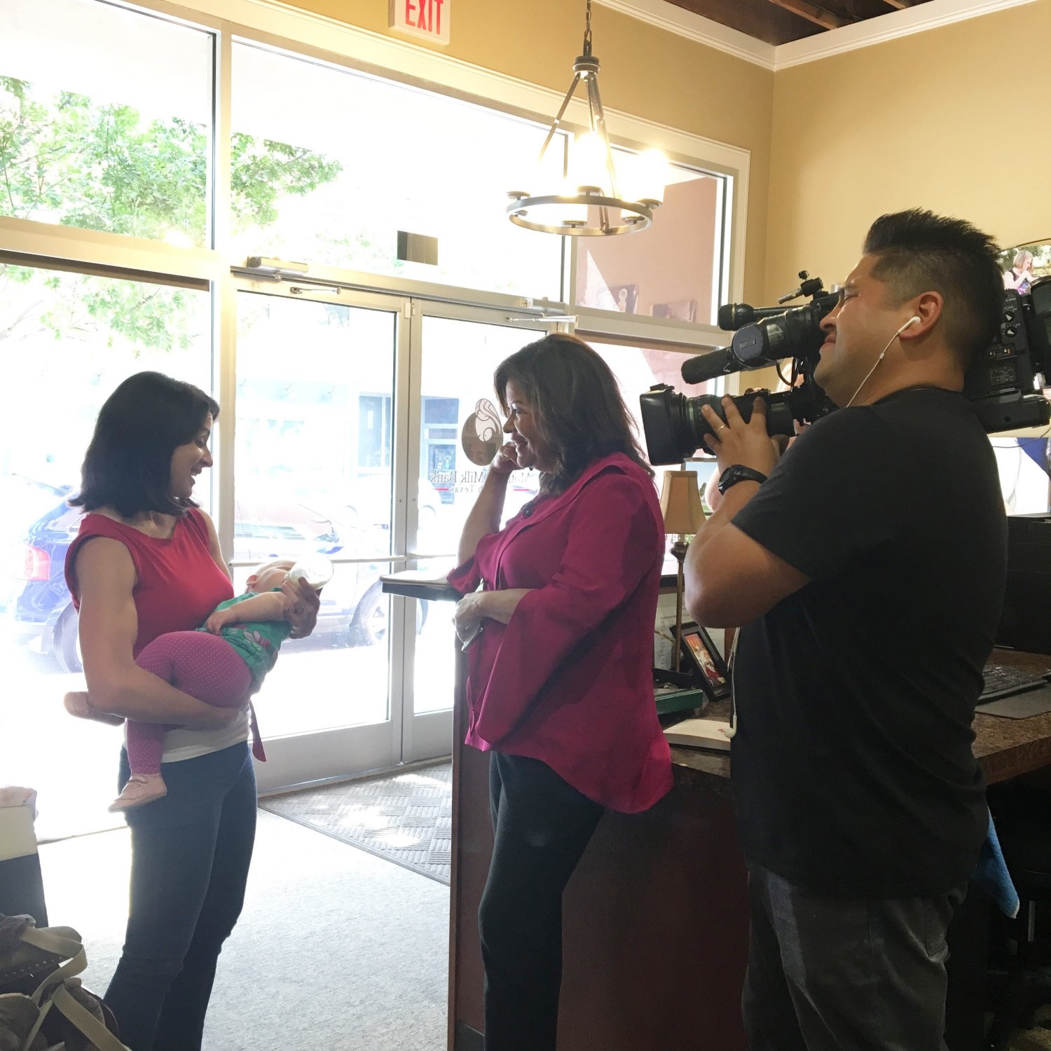 Journalist interviewing mother holding baby while cameraman films