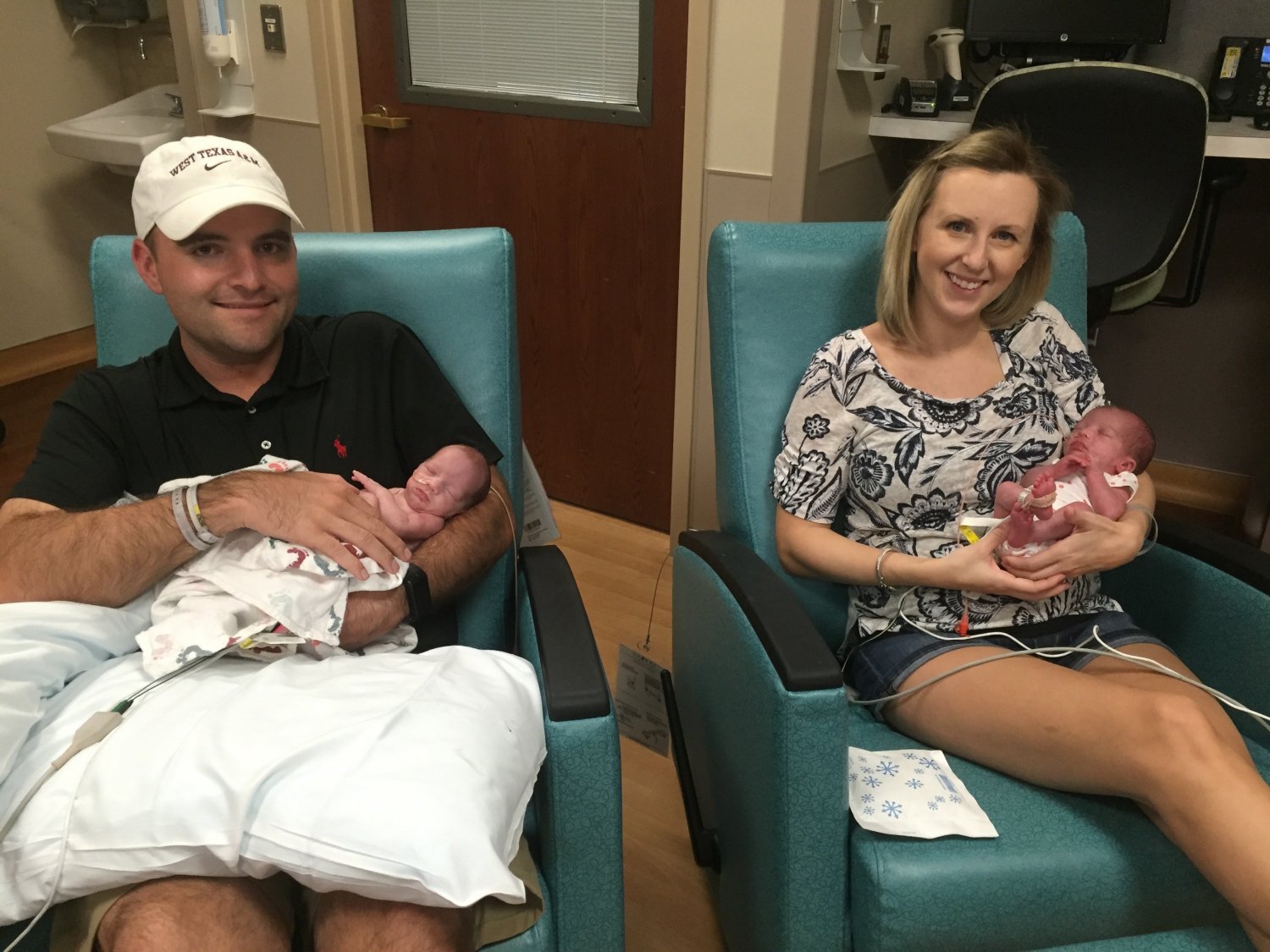 Mother and father each holding one twin daughter in hospital