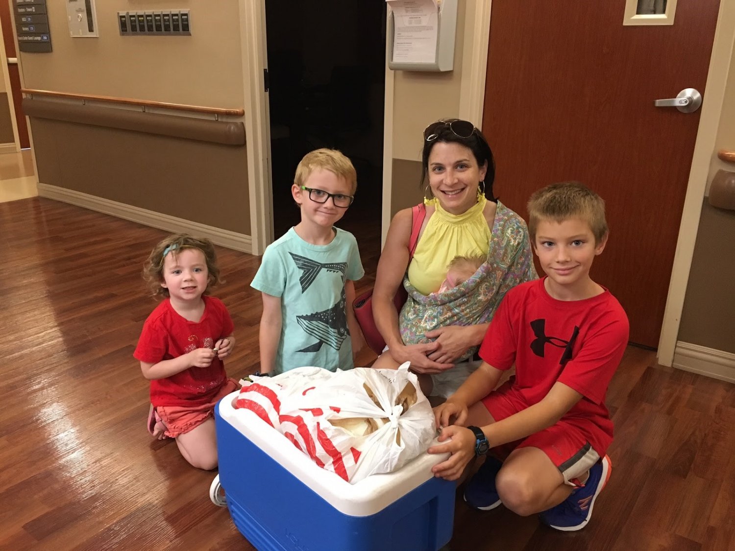 Mother and 4 children with cooler of frozen breastmilk