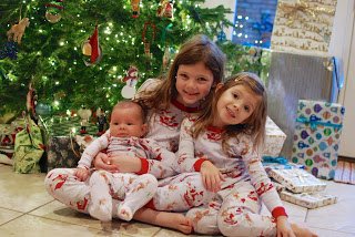 Two young sisters holding their baby brother