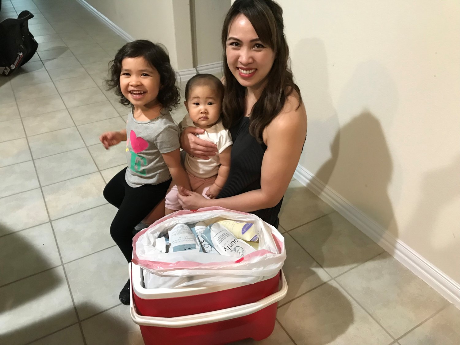 Mother, baby and toddler next to cooler full of frozen breastmilk