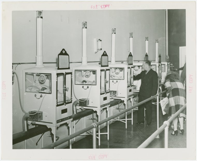 Men and women looking at babies in incubators